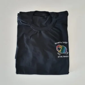 uma camisa preta com um bordado no lado esquerdo, com uma ovelha com as cores da bandeira lgbtqia+ e a frase rainbow sheep acima e of the family, abaixo, em branco