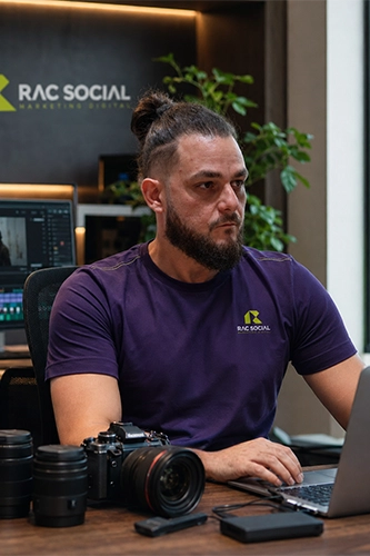 imagem do Cauê usando uniforme da RAC, roxo, sentado, usando um notebook